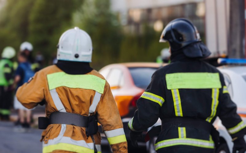 Group of fire men in uniform during fire fighting operation in the city streets, firefighters with fire engine truck vehicle in the background, emergency and rescue, fire drill, exercise training